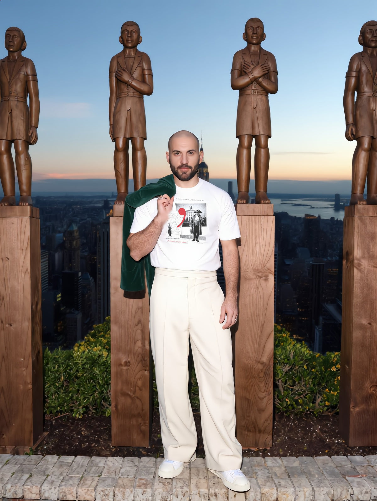 Man among wooden statues on a New York rooftop, wearing Plate XXI